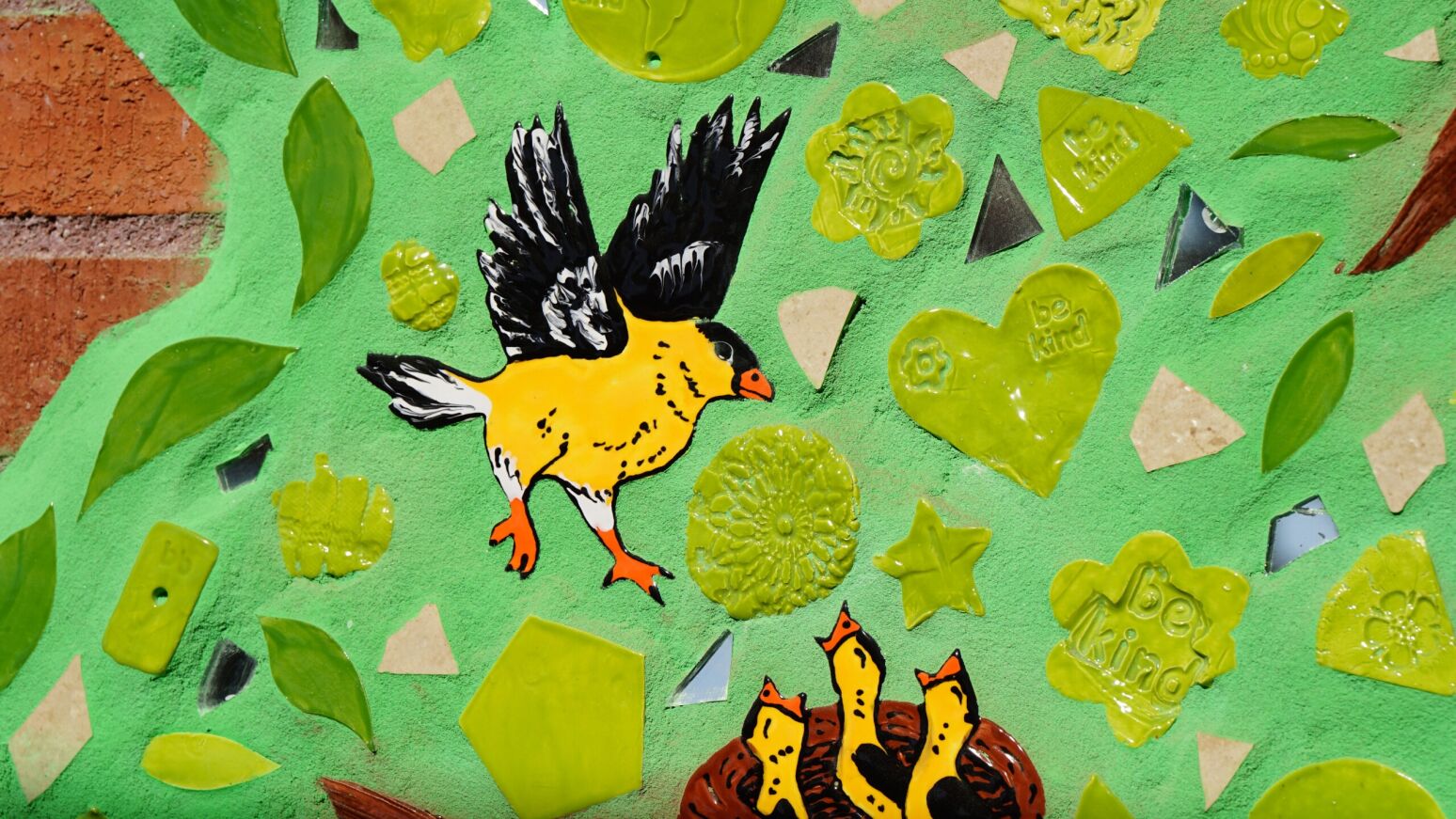 A closeup of one of Steele's new Be Kind mosaics depicting a yellow bird and a nest of baby birds