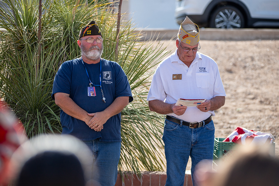 Two men from the VFW stand in front of a group of students