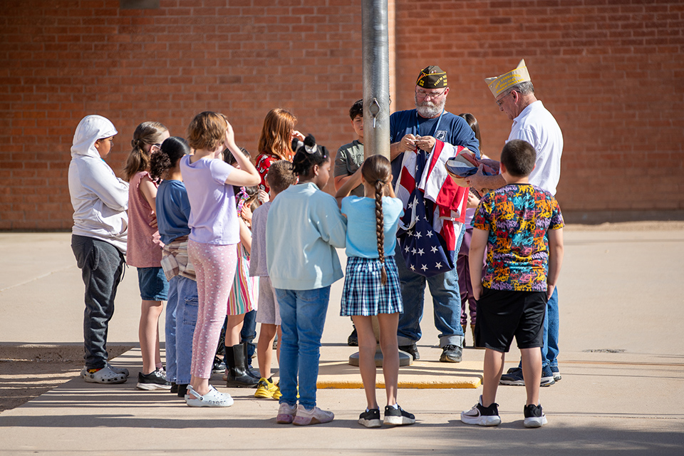 Students stand around the flag pole before the flag is raised