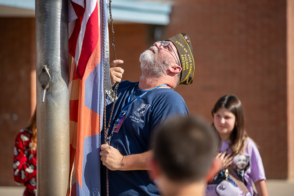 A man from the VFW raises the American flag on the school's flagpole