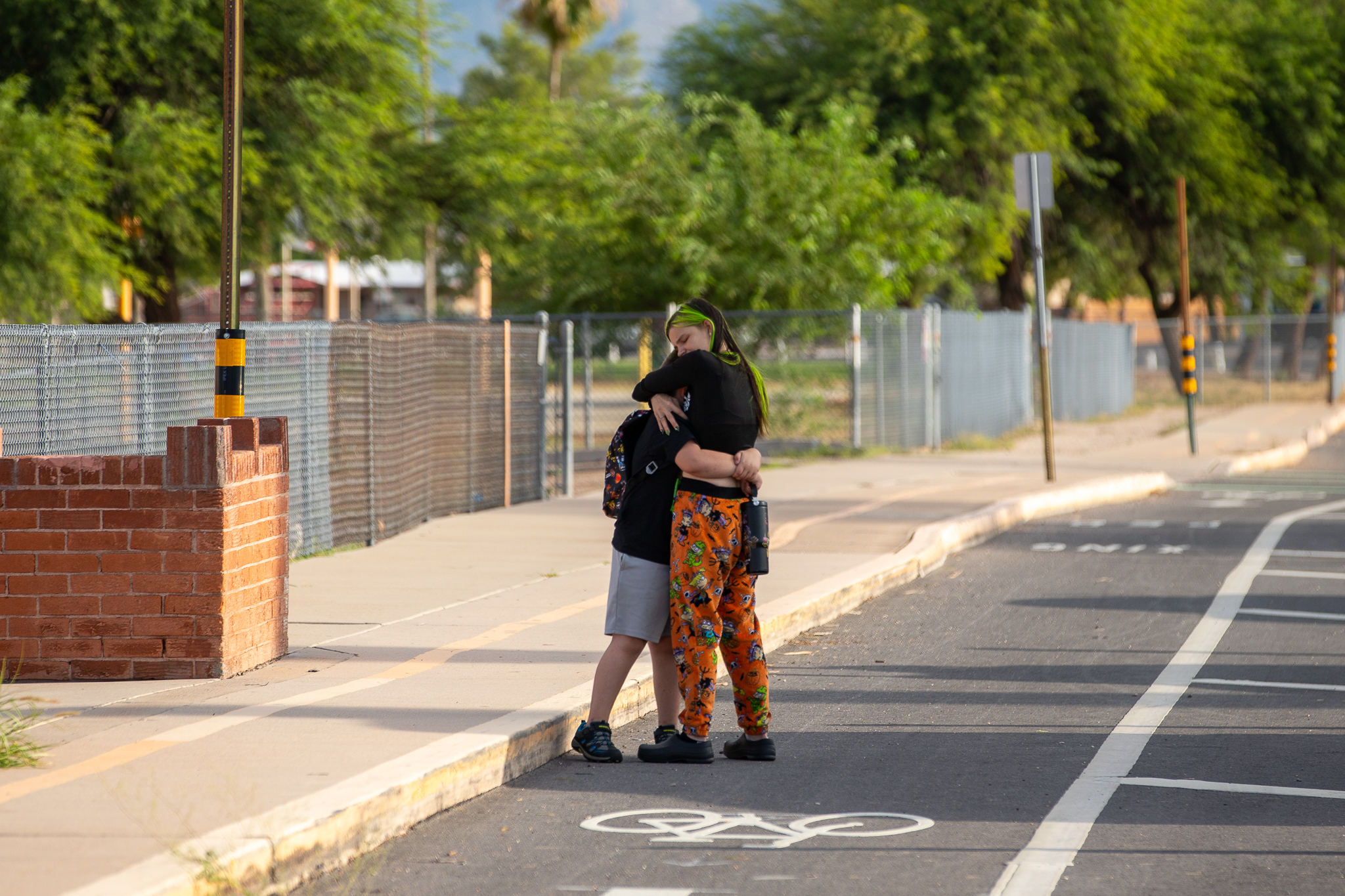 A mom hugs her kid outside school on the first day