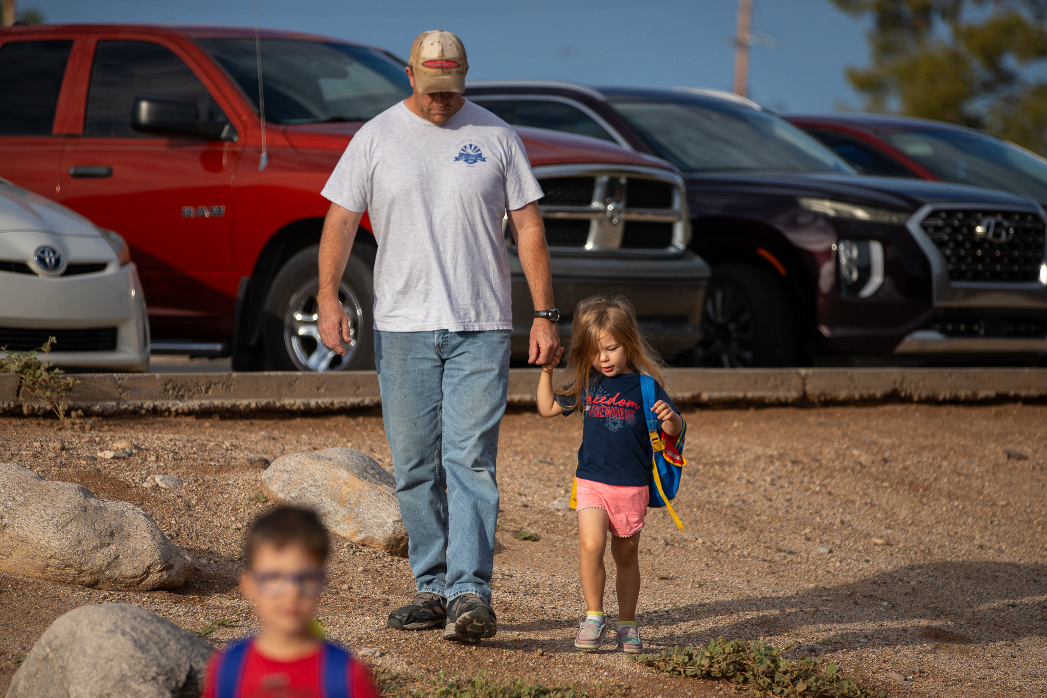 A dad walks with his young daughter into school
