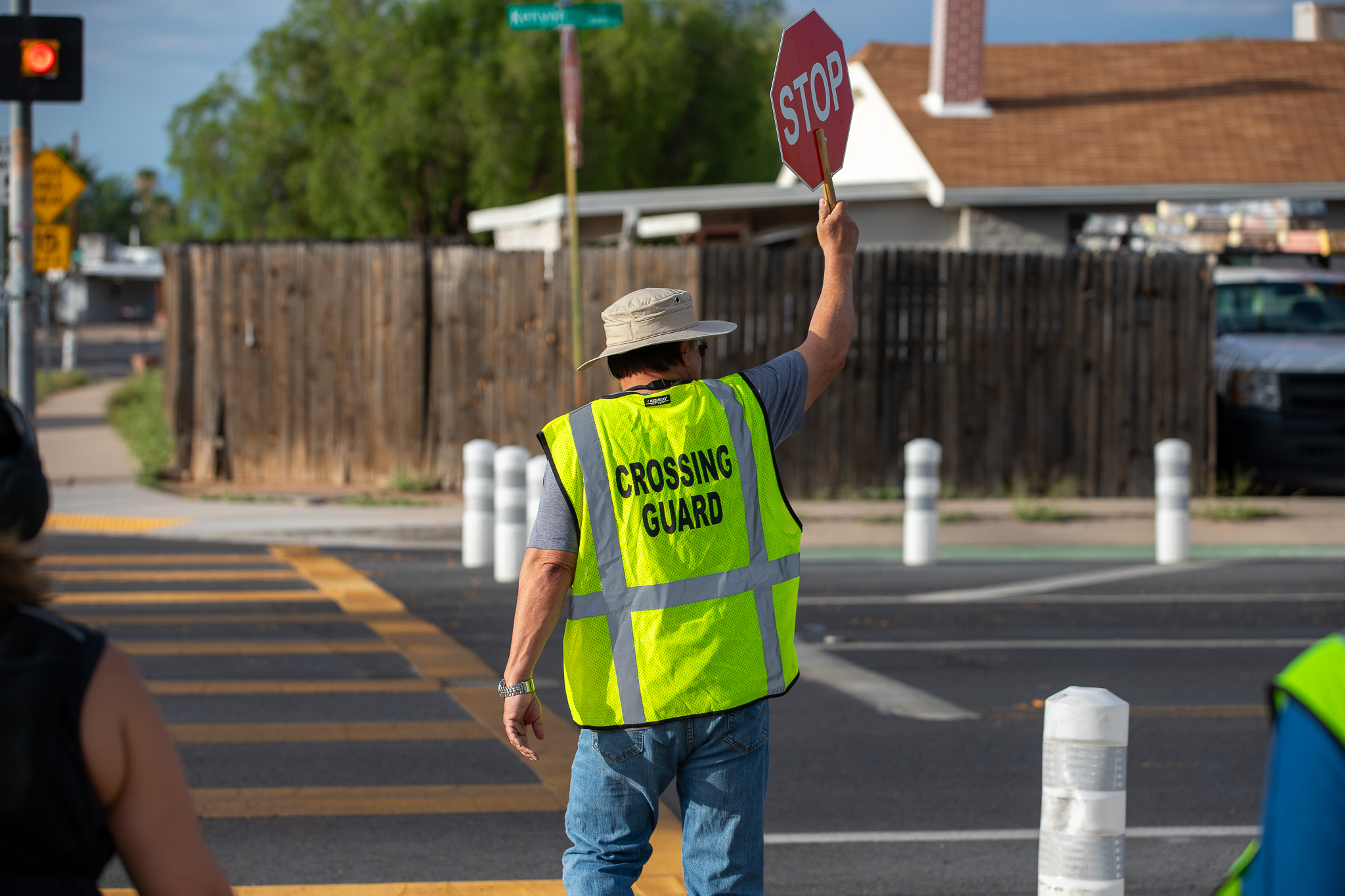The crossing guard holds up his stop sign as he crosses the street